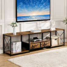 A rustic industrial TV stand with a wood top and frame, black metal legs, and open shelving, styled in a living room setting under a wall-mounted TV.